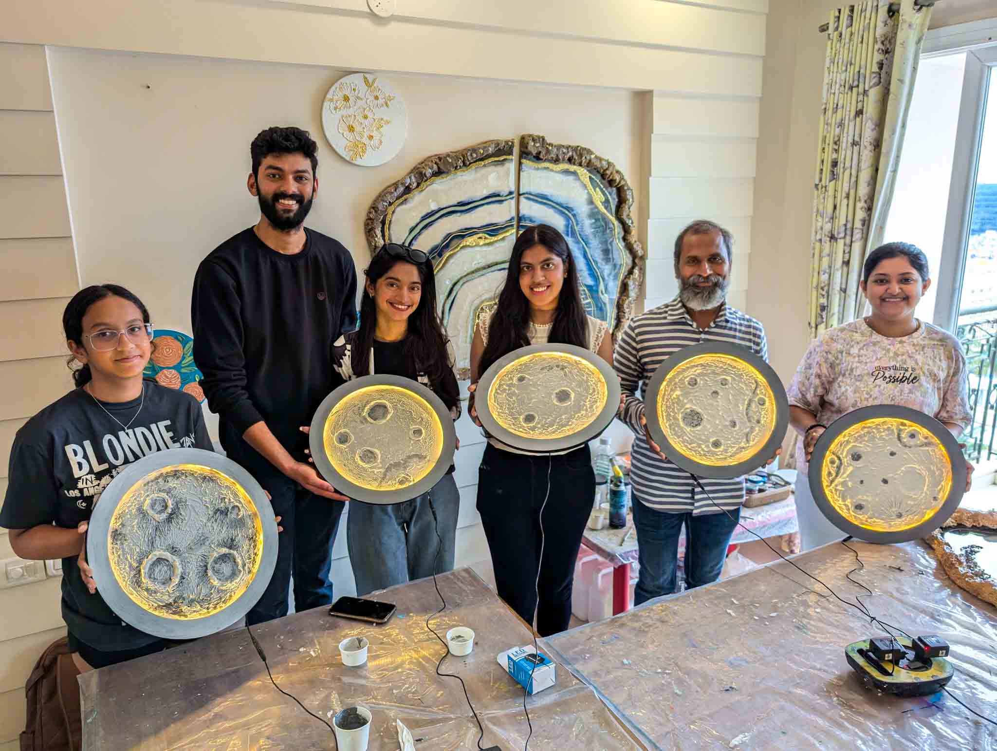 Group of participants standing inside a workshop holding their completed glowing moon lamps.